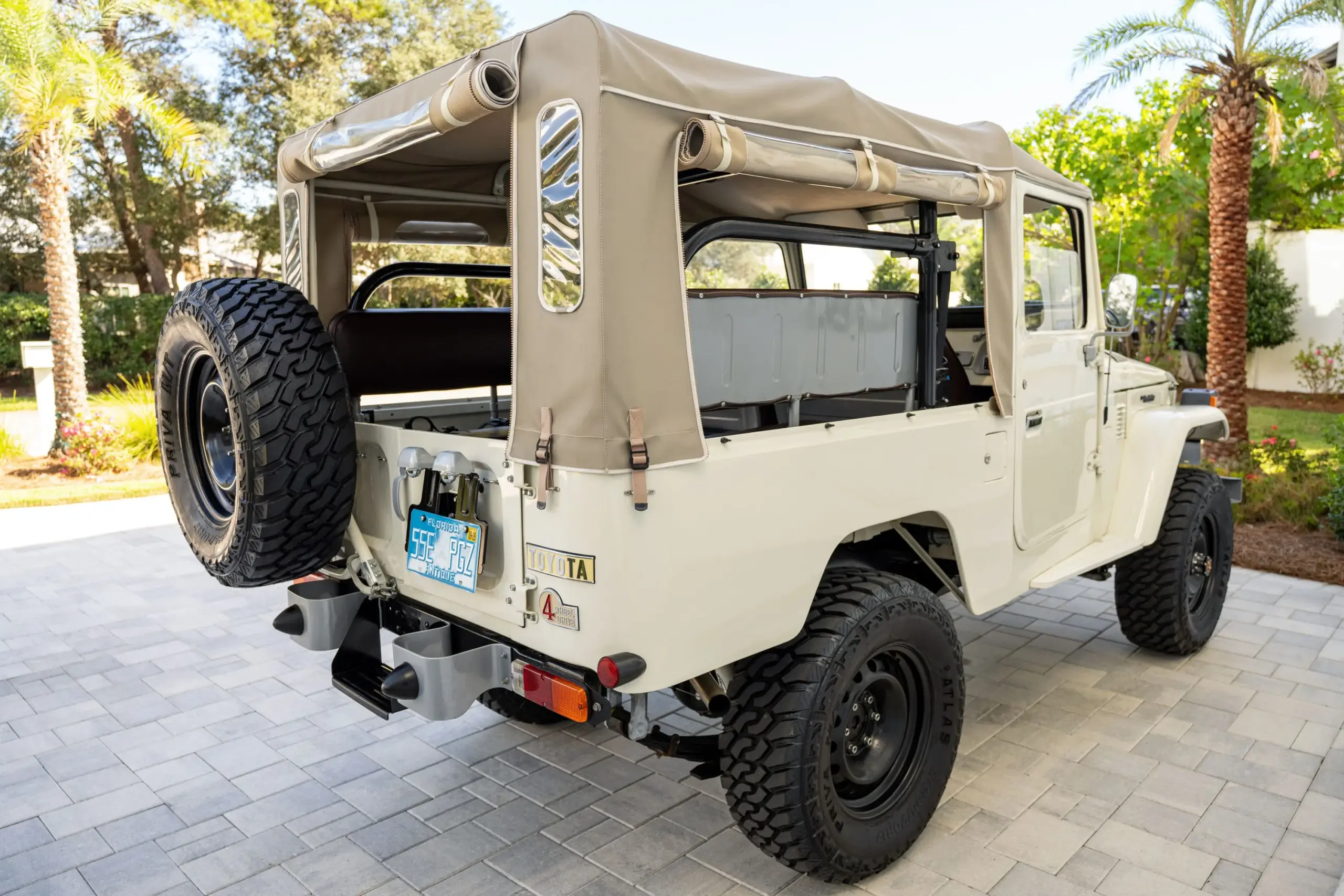 Rückansicht eines weißen, restaurierten Toyota Land Cruiser FJ43 von 1982 mit beige Softtop und großem Ersatzrad