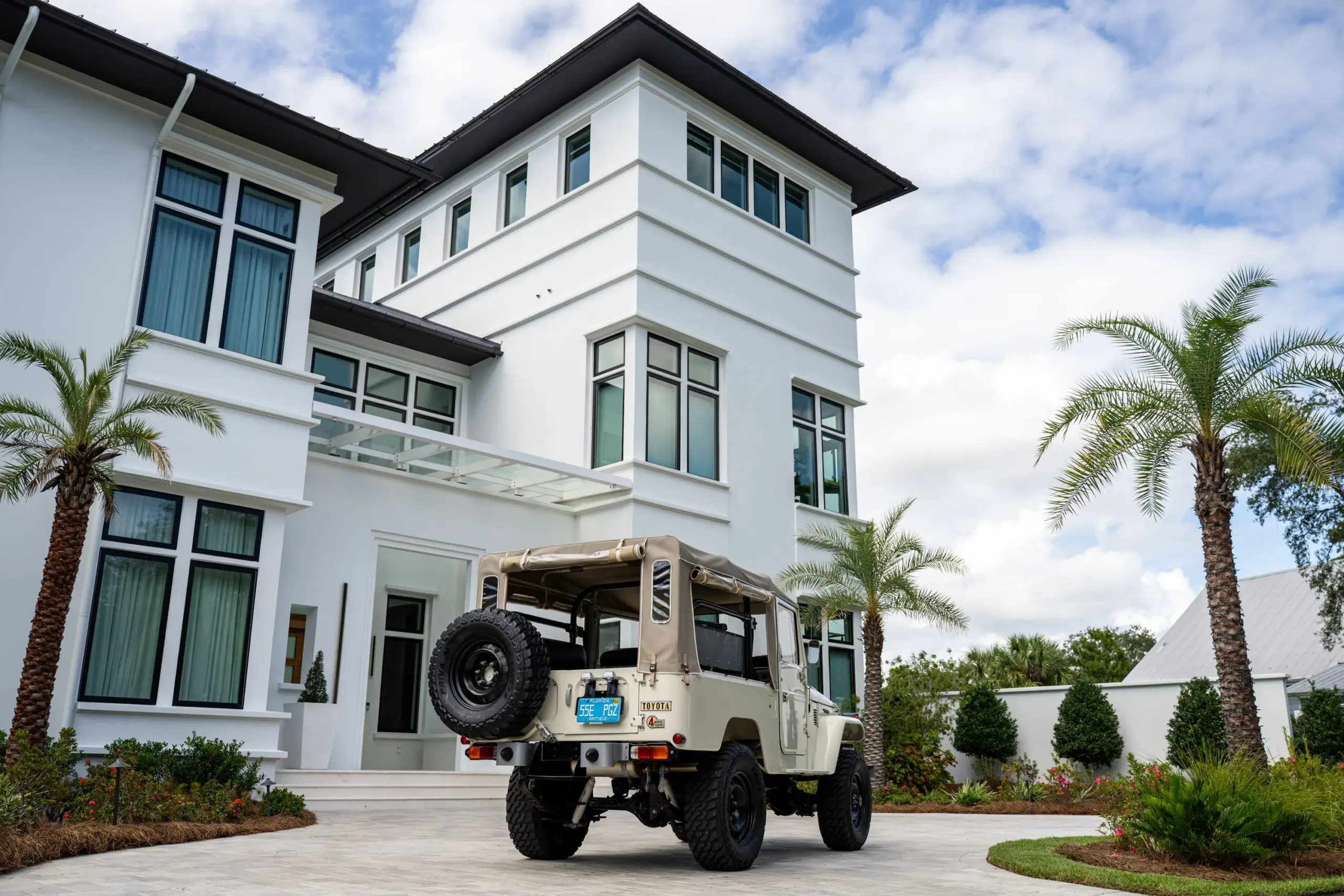 Toyota Land Cruiser FJ43 (1982) mit beige Softtop und Ersatzradträger vor weißem, modernen Wohnhaus