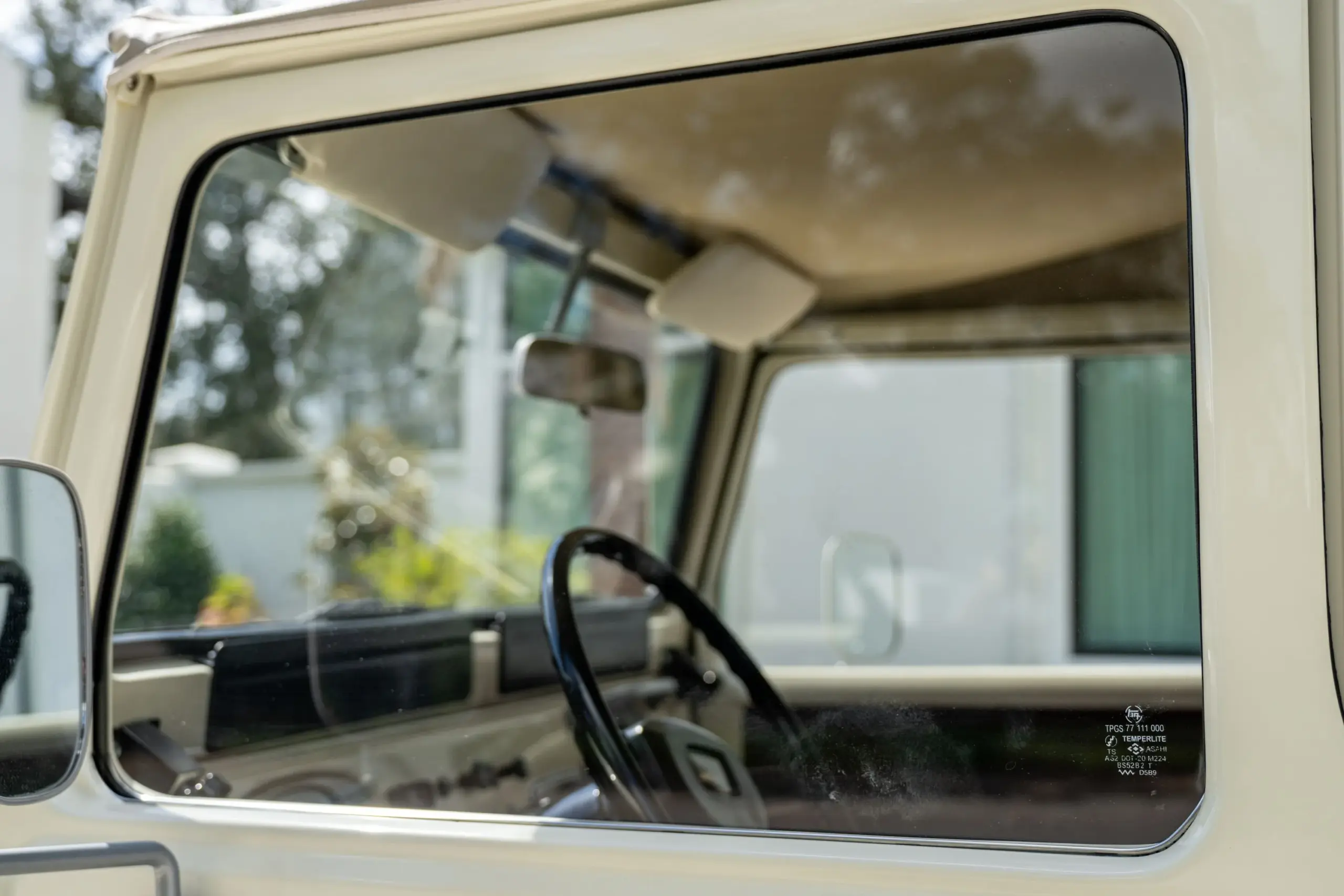 Blick durch das Seitenfenster auf das Lenkrad und Armaturenbrett eines restaurierten Toyota Land Cruiser FJ43, Baujahr 1982.