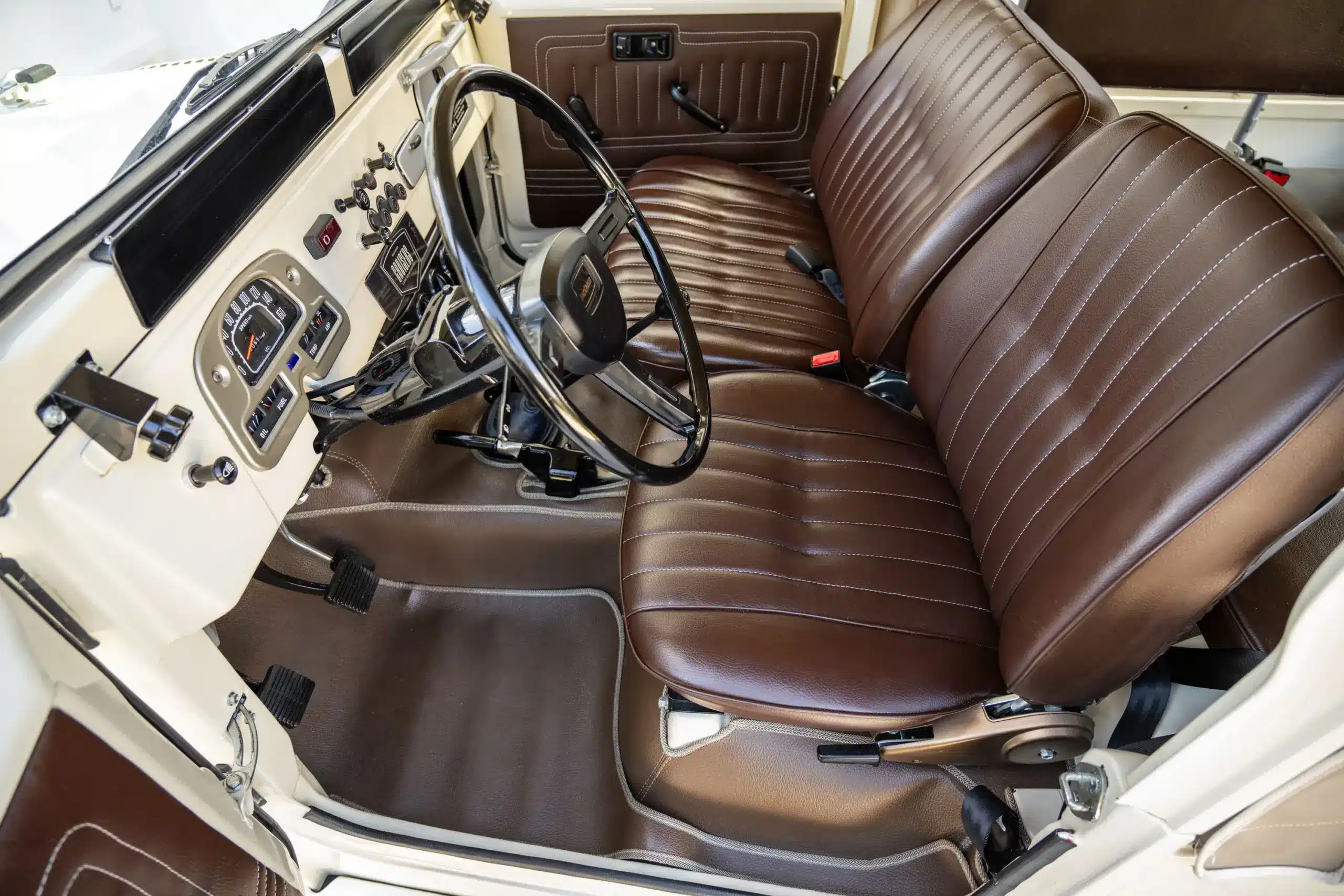 Restaurierter Innenraum eines Toyota Land Cruiser FJ43 mit braunen Vordersitzen aus Vinyl und klassischem Armaturenbrett