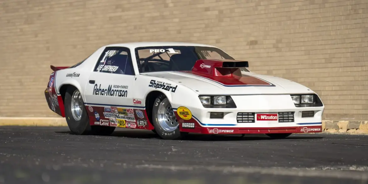 1984 Chevrolet Camaro Pro Stock Dragster Rennauto mit Sponsorenlogos, gebaut von Reher-Morrison und gefahren von Lee Shepherd, steht schräg vor einer Backsteinwand