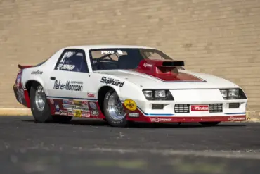 1984 Chevrolet Camaro Pro Stock Dragster Rennauto mit Sponsorenlogos, gebaut von Reher-Morrison und gefahren von Lee Shepherd, steht schräg vor einer Backsteinwand