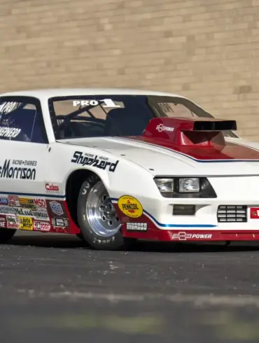 1984 Chevrolet Camaro Pro Stock Dragster Rennauto mit Sponsorenlogos, gebaut von Reher-Morrison und gefahren von Lee Shepherd, steht schräg vor einer Backsteinwand