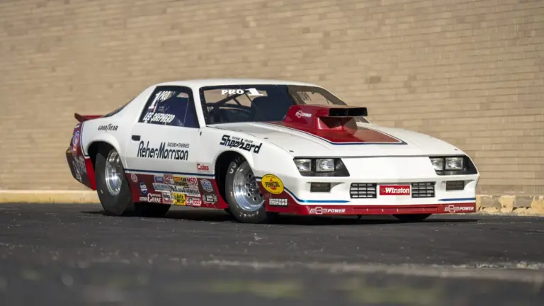 1984 Chevrolet Camaro Pro Stock Dragster Rennauto mit Sponsorenlogos, gebaut von Reher-Morrison und gefahren von Lee Shepherd, steht schräg vor einer Backsteinwand