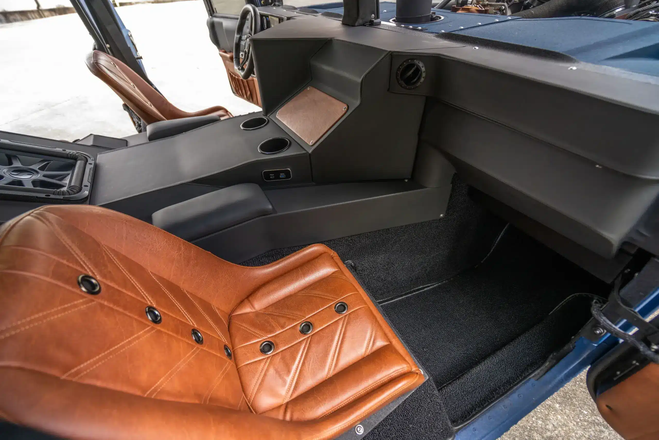 Blick auf das Interieur eines umgebauten Humvee mit braunem Leder-Bomber-Sitz, schwarzer Mittelkonsole und hochwertigen Oberflächen.