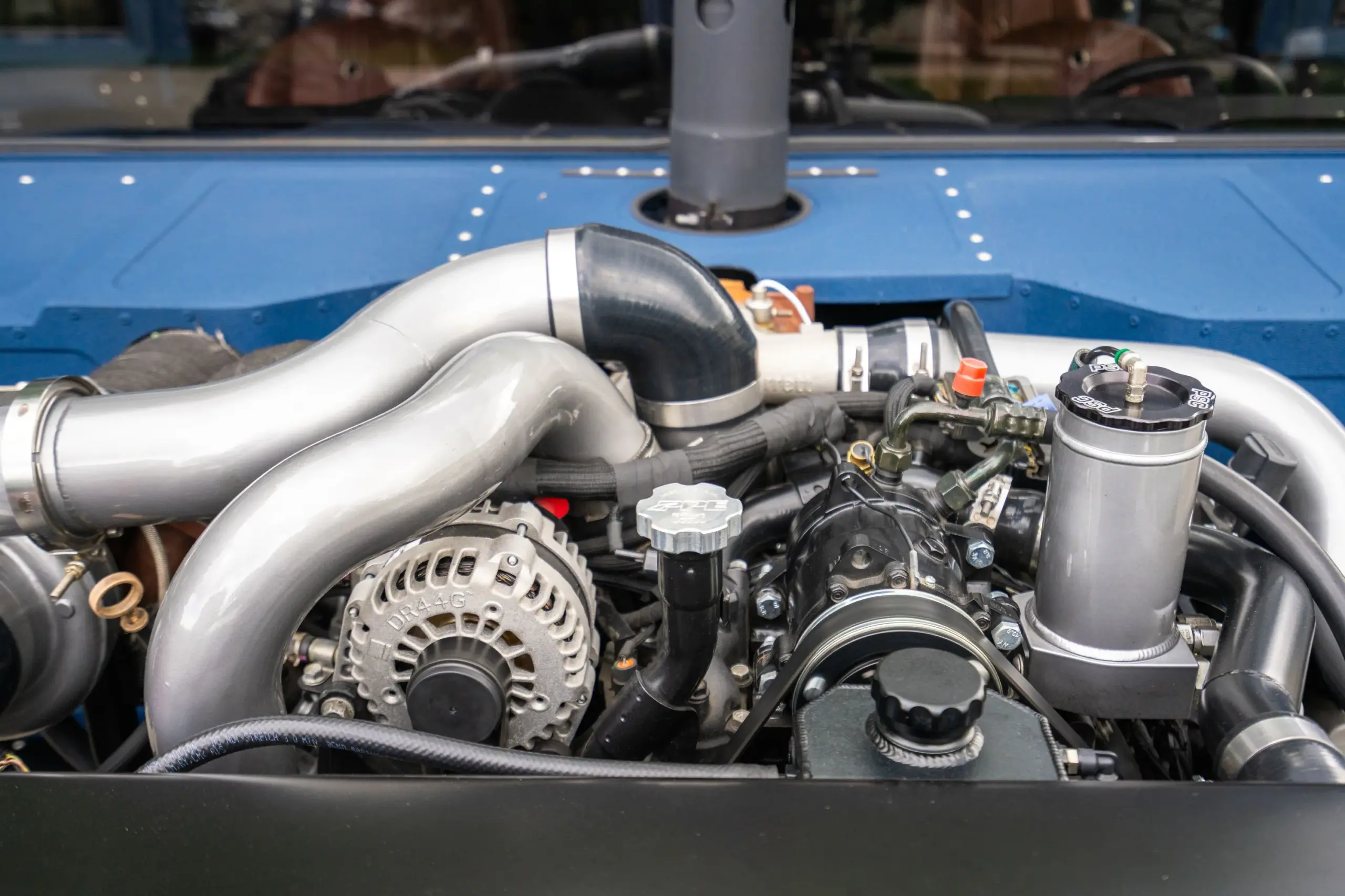 Nahaufnahme des Motors eines 1987er Humvee-Restomods mit sichtbaren Turboladern, Ladeluftleitungen und zentraler Auspuffsäule.