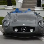 Grauer S-Klub LA Roadster, inspiriert vom Mercedes 300 SLR, mit blauen Sitzen und markanter Frontpartie, stehend vor Treppe und weißer Mauer.