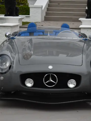 Grauer S-Klub LA Roadster, inspiriert vom Mercedes 300 SLR, mit blauen Sitzen und markanter Frontpartie, stehend vor Treppe und weißer Mauer.
