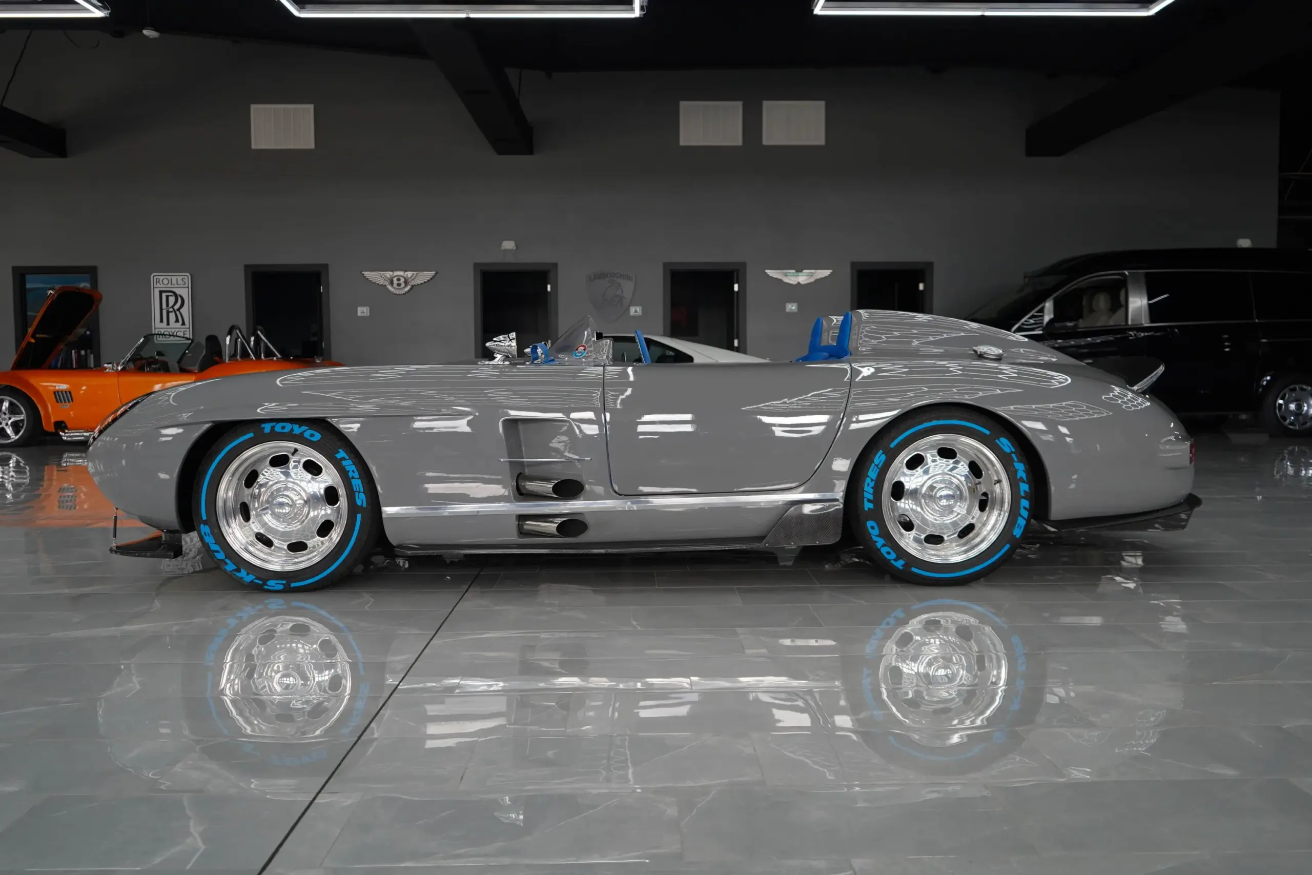 Seitenansicht eines S‑Klub LA Roadster-Unikats in Nardo-Grau mit blauen Rennsitzen und TOYO-Reifen, inspiriert vom Mercedes-Benz 300 SLR.