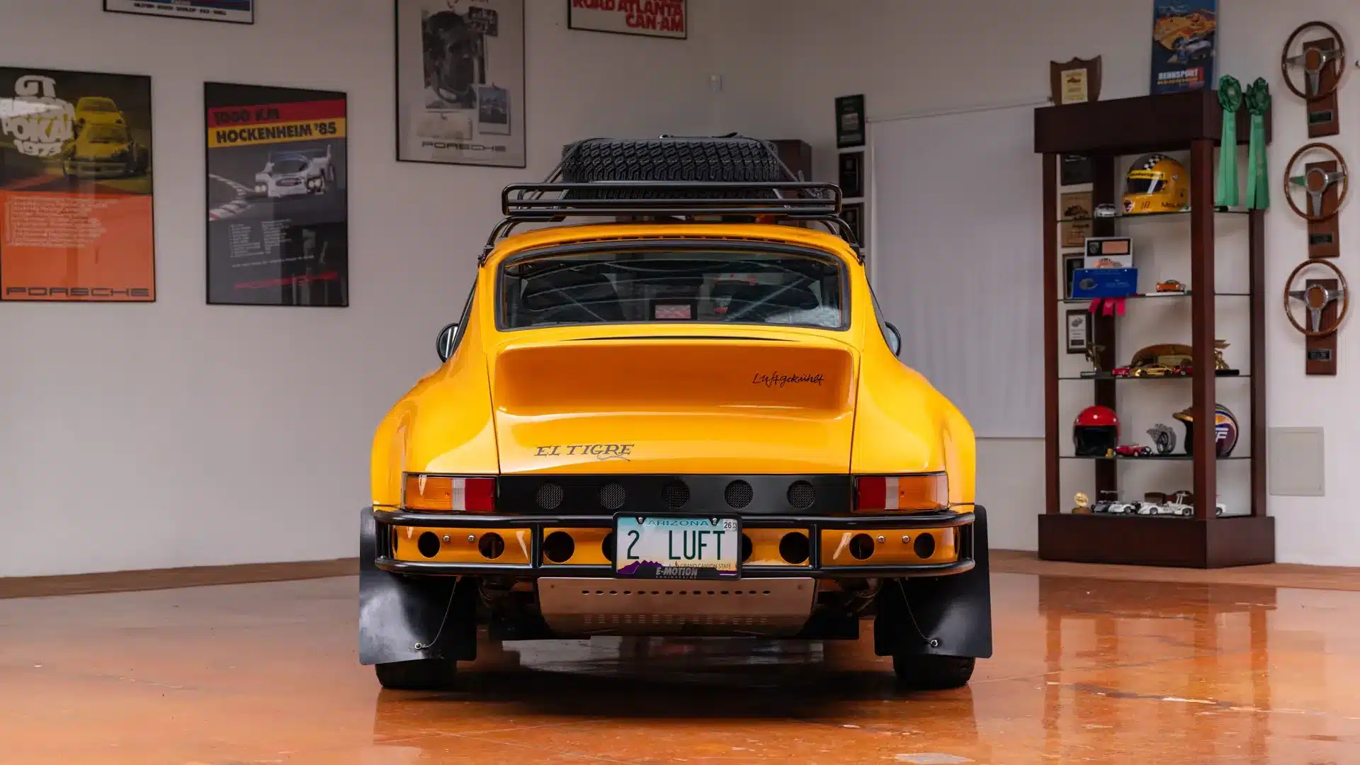 Heckansicht eines gelben Porsche 911 Safari Umbau mit Dachträger und Offroad-Ausstattung in einer Garage.