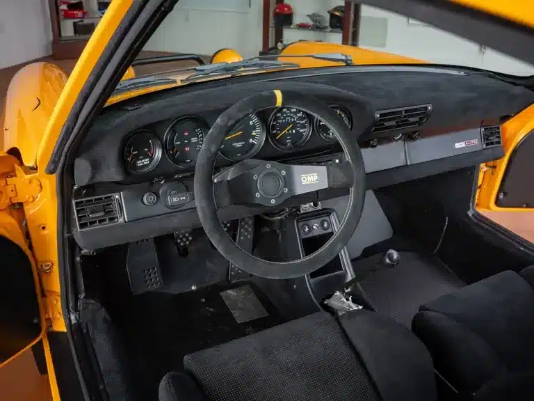 Innenraum eines Porsche 911 Safari von 1987 mit OMP-Lenkrad und sportlicher Armaturentafel, Blick auf die Instrumente.