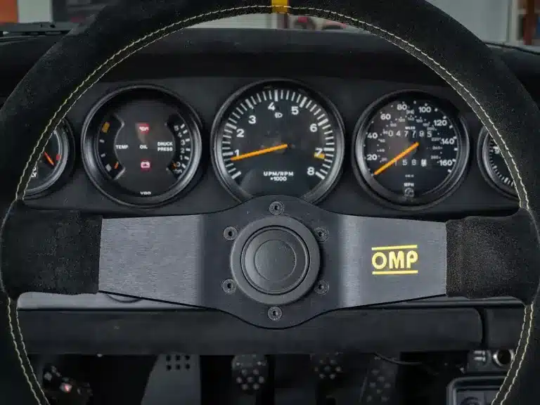 Detailansicht des Cockpits eines Porsche 911 Safari von 1987 mit OMP-Lenkrad und klassischen Rundinstrumenten.