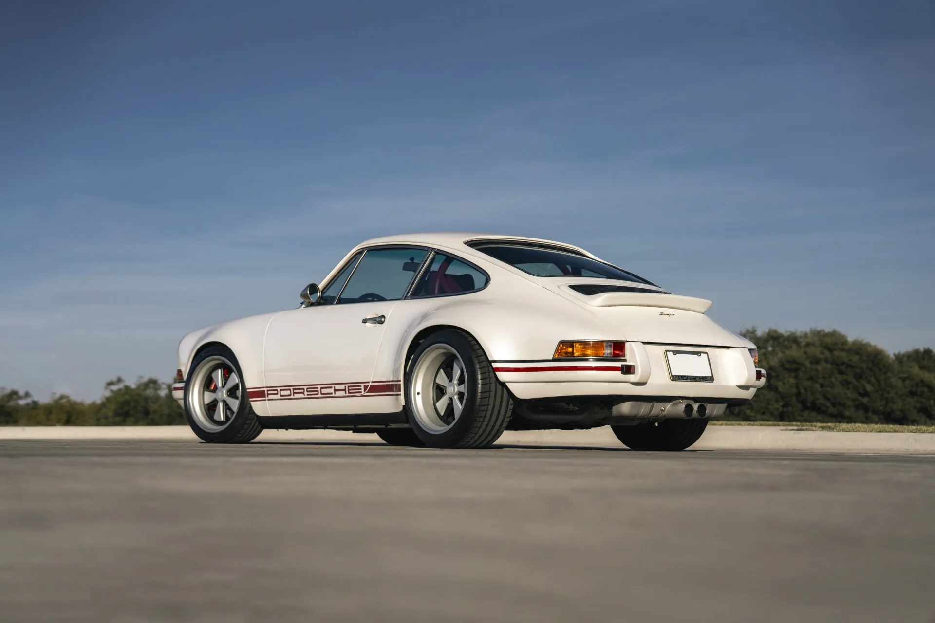 Rückansicht eines weißen Porsche 911 Carrera Classic Study by Singer, seitlich fotografiert bei Tageslicht.