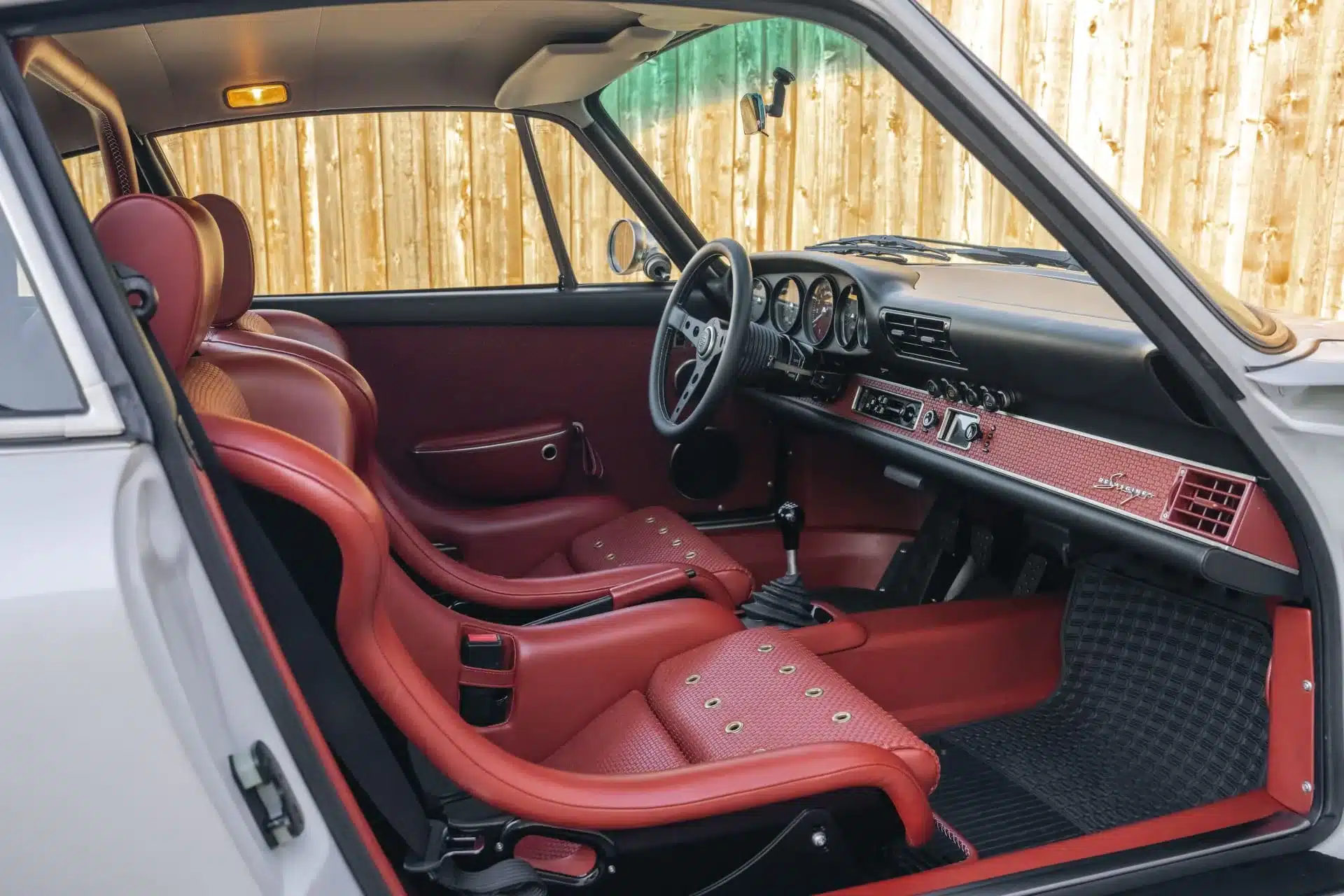 Detaillierte Ansicht des roten Interieurs eines restaurierten 1990er Porsche 911 Carrera Classic Study von Singer, Blick auf Sitze, Armaturenbrett und Schalthebel