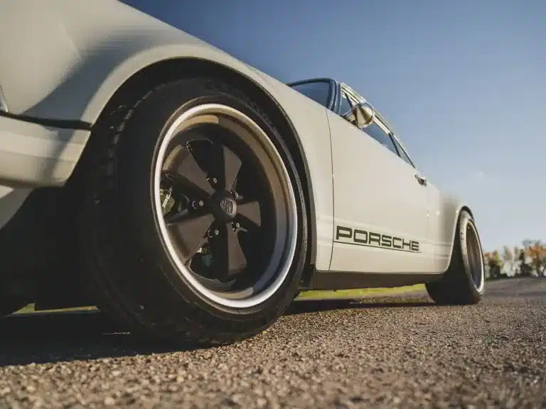 Seitliche Nahaufnahme eines Singer Porsche 911 Novato mit grünem Porsche-Schriftzug und RSR-Felgen auf Asphalt