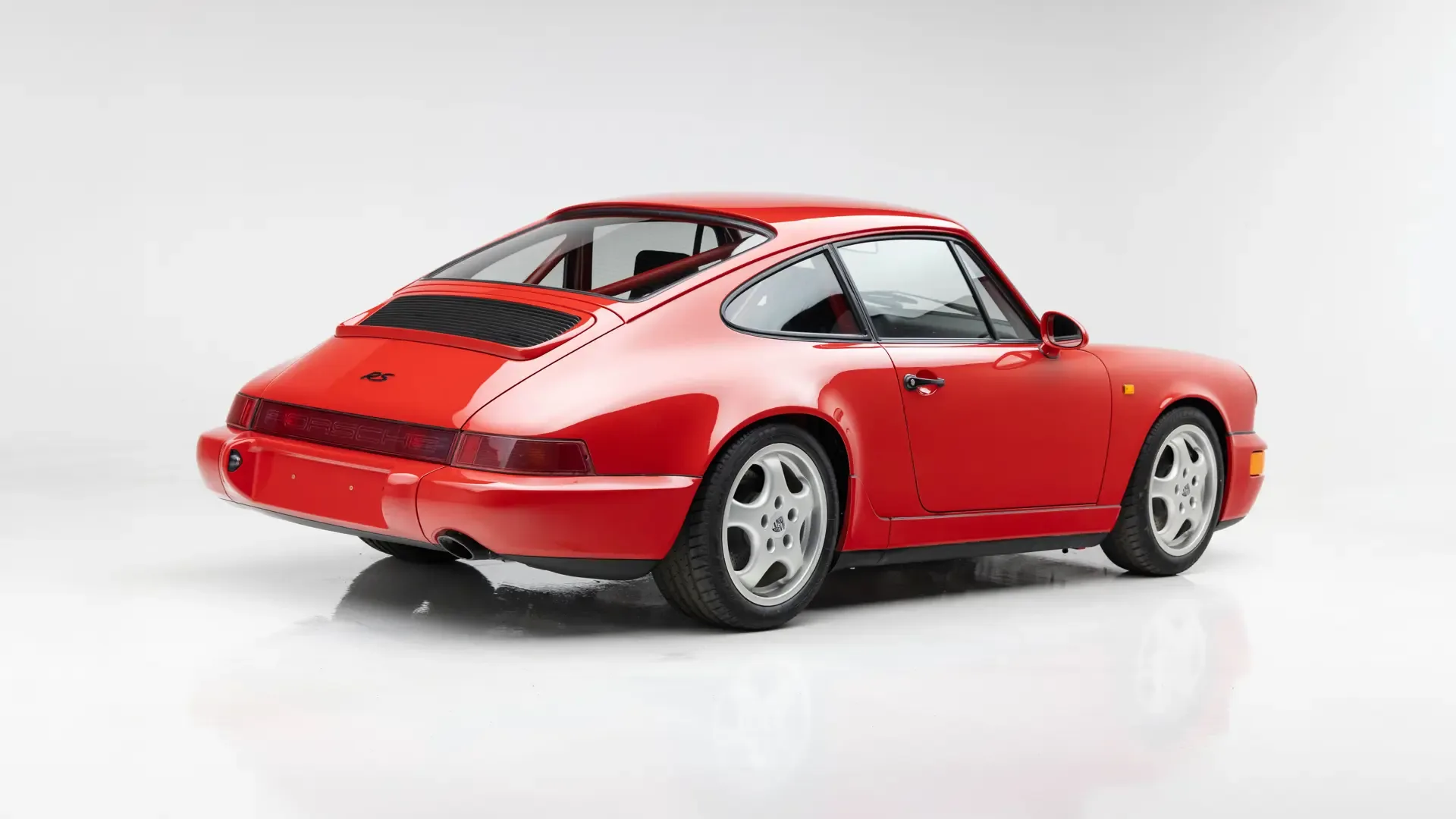 Roter Porsche 911 Carrera RS N/GT aus dem Jahr 1992, fotografiert im Studio mit klarem Blick auf das Heck und die Seite