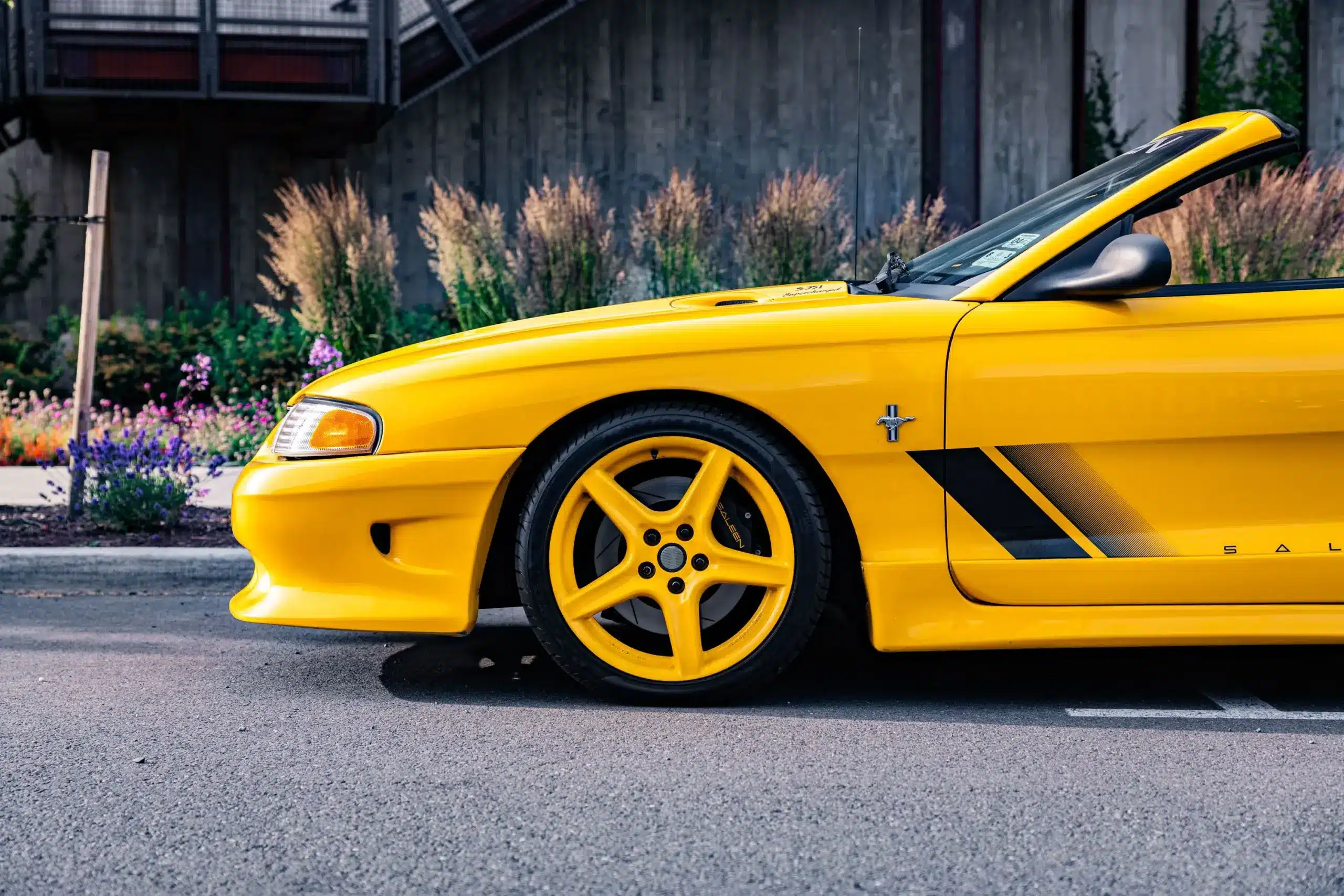 Gelber 1995 Saleen Mustang S351 Cabrio, Seitenansicht der Frontpartie mit originalen Felgen und Seitendekor.