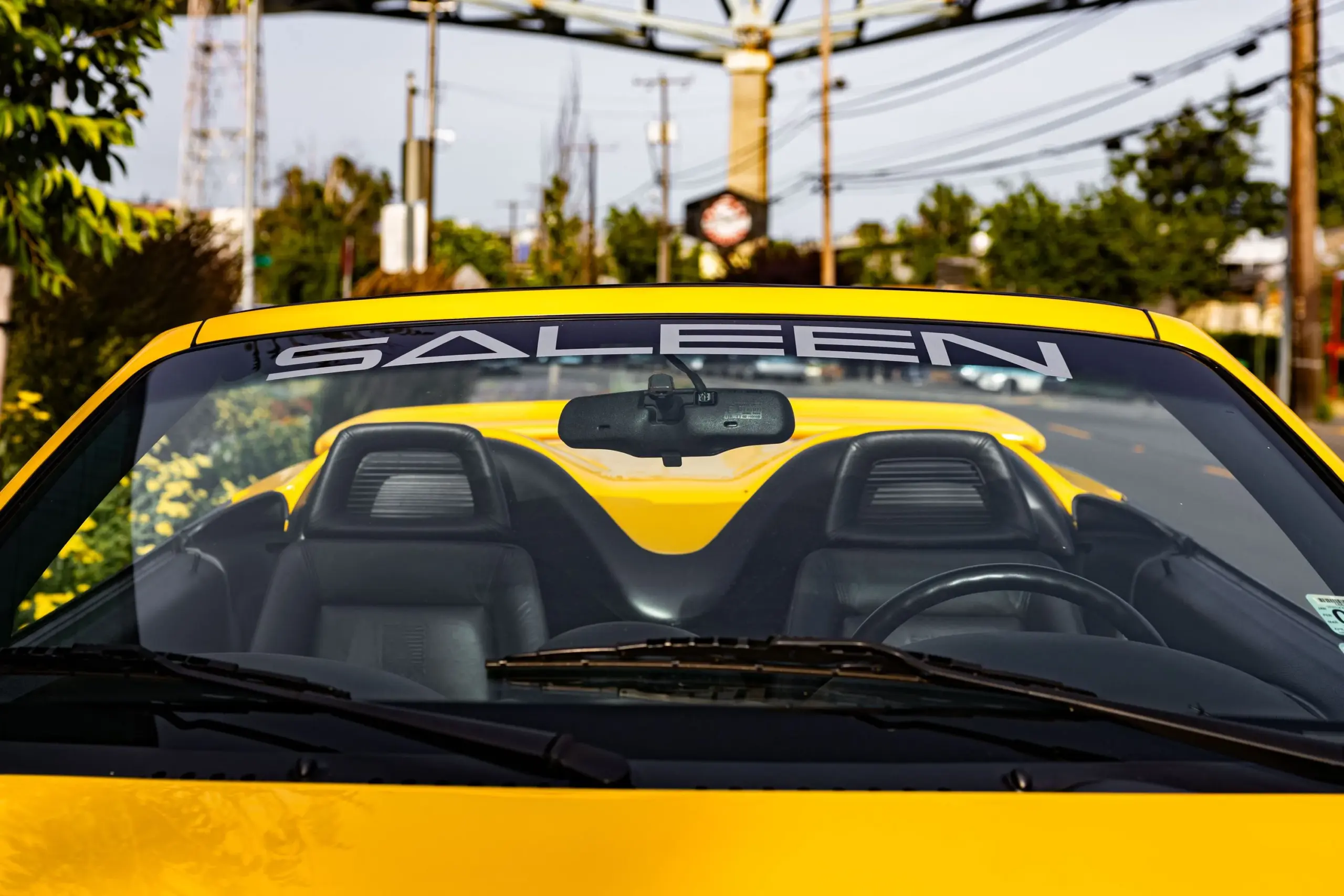Nahaufnahme der Windschutzscheibe mit SALEEN-Logo eines gelben Saleen Mustang S351 Cabriolets von 1995