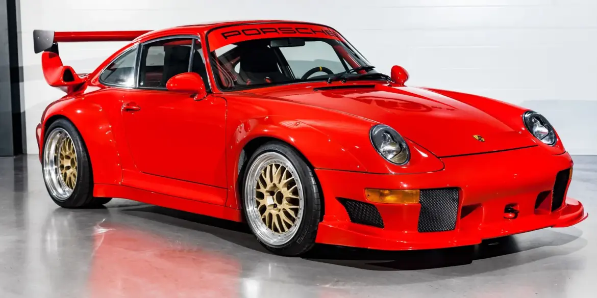 Seitenansicht eines roten Porsche 911 (993) GT2 Evo Umbaus mit breiten Kotflügeln, großem Heckflügel und goldenen BBS Felgen.