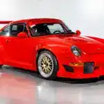 Seitenansicht eines roten Porsche 911 (993) GT2 Evo Umbaus mit breiten Kotflügeln, großem Heckflügel und goldenen BBS Felgen.