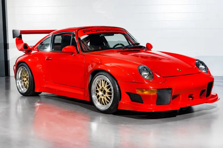 Seitenansicht eines roten Porsche 911 (993) GT2 Evo Umbaus mit breiten Kotflügeln, großem Heckflügel und goldenen BBS Felgen.