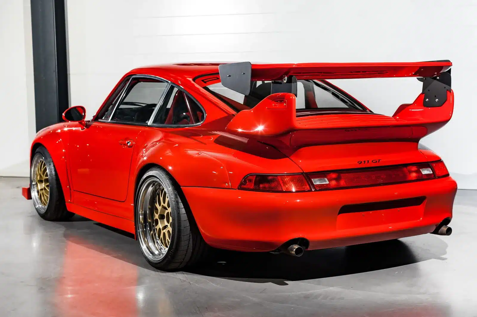 Roter Porsche 911 (993) GT2-Evo Umbau mit großem Heckspoiler und goldenen BBS-Felgen, Ansicht von hinten.