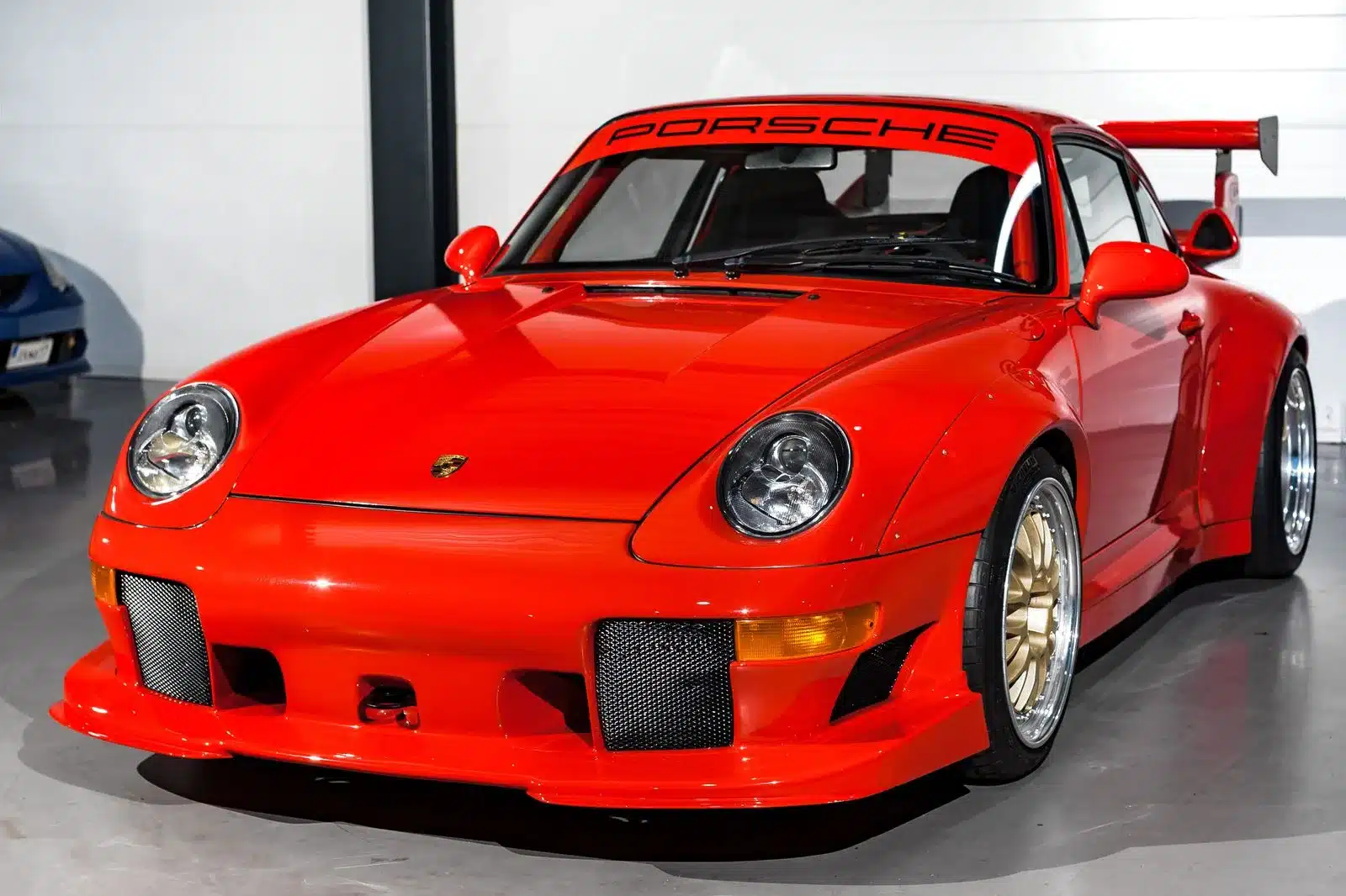 Guards Red Porsche 911 993 GT2-Evo Umbau mit breiten Kotflügeln, großem Heckflügel und goldenen BBS-Felgen.