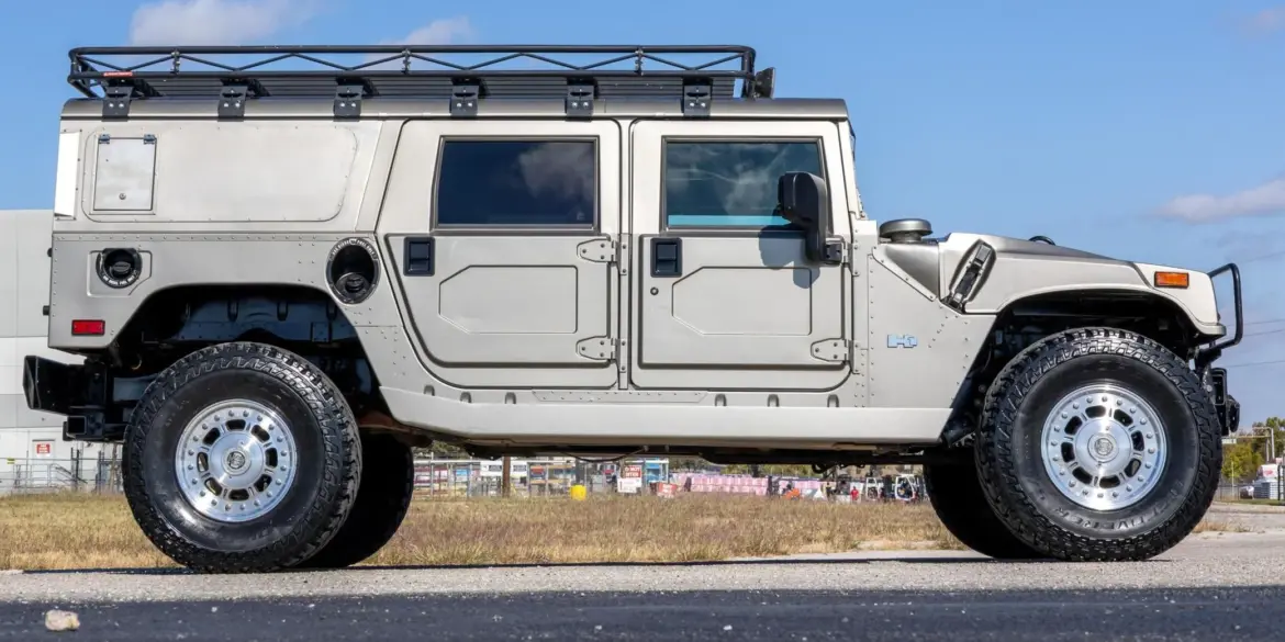 2002 Hummer H1 Wagon in Silber, Seitenansicht mit Dachgepäckträger, auf offener Fläche stehend
