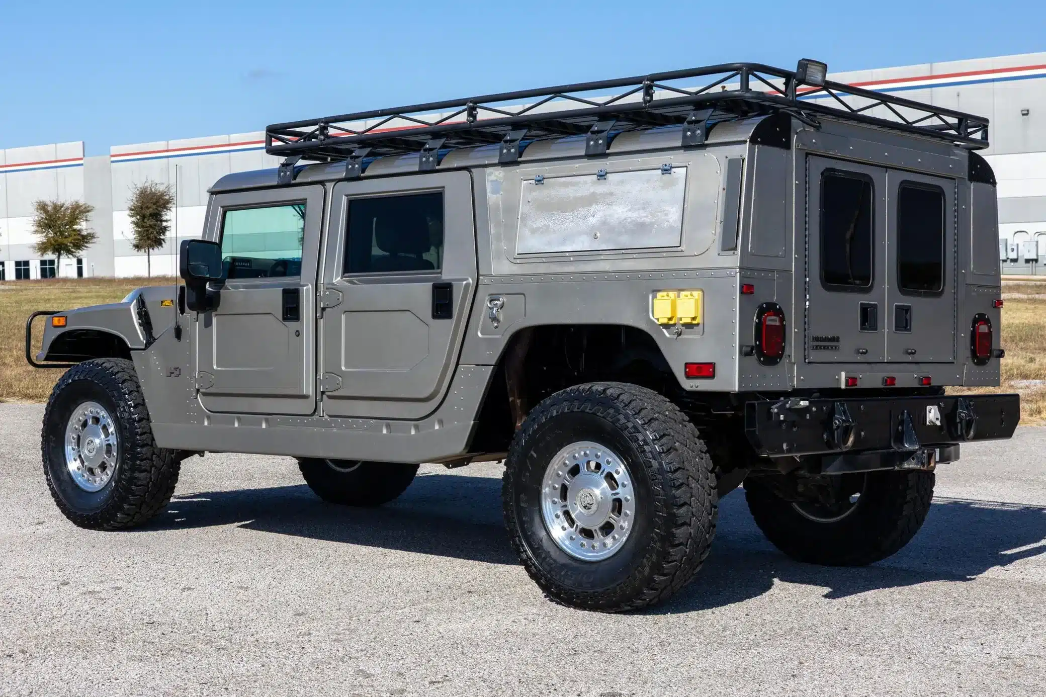 2002 Hummer H1 Wagon in Grau mit Dachgepäckträger, aufgenommen im Freien von hinten seitlich.