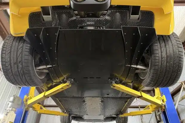 Unterbodenansicht eines gelben Ford GT mit sichtbarem Diffusor und Aluminium-Raumrahmen auf einer Hebebühne
