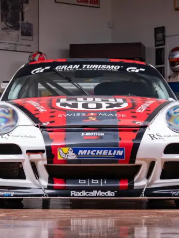 2007 Porsche 911 GT3 Cup Rennwagen, frontal aufgenommen, mit rotem und schwarzem Renn-Design und Sponsorlogos, in einer Motorsport-Garage.