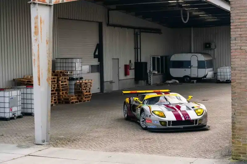 Silberner Ford GT1-by-Matech Rennwagen mit gelben und roten Akzenten, steht in einer offenen Lagerhalle.