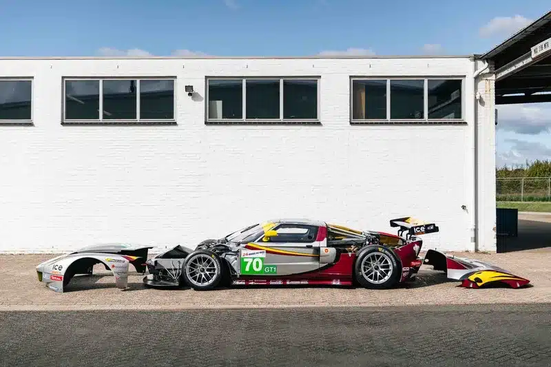 Silberner GT1-by-Matech Rennwagen von 2010, teildemontiert, vor einem weißen Gebäude