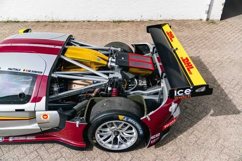 GT1-by-Matech Rennwagen, Baujahr 2010, in Silber mit geöffnetem Heck und sichtbarer Renntechnik.