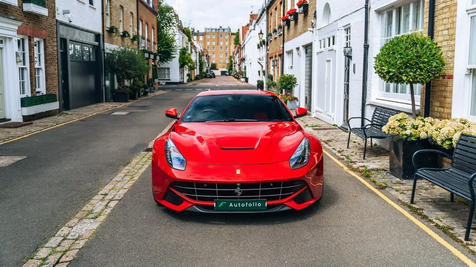 Roter Ferrari F12 Berlinetta aus dem Jahr 2013 mit rechtslenkung, fotografiert frontal in einer ruhigen Wohnstraße in London.