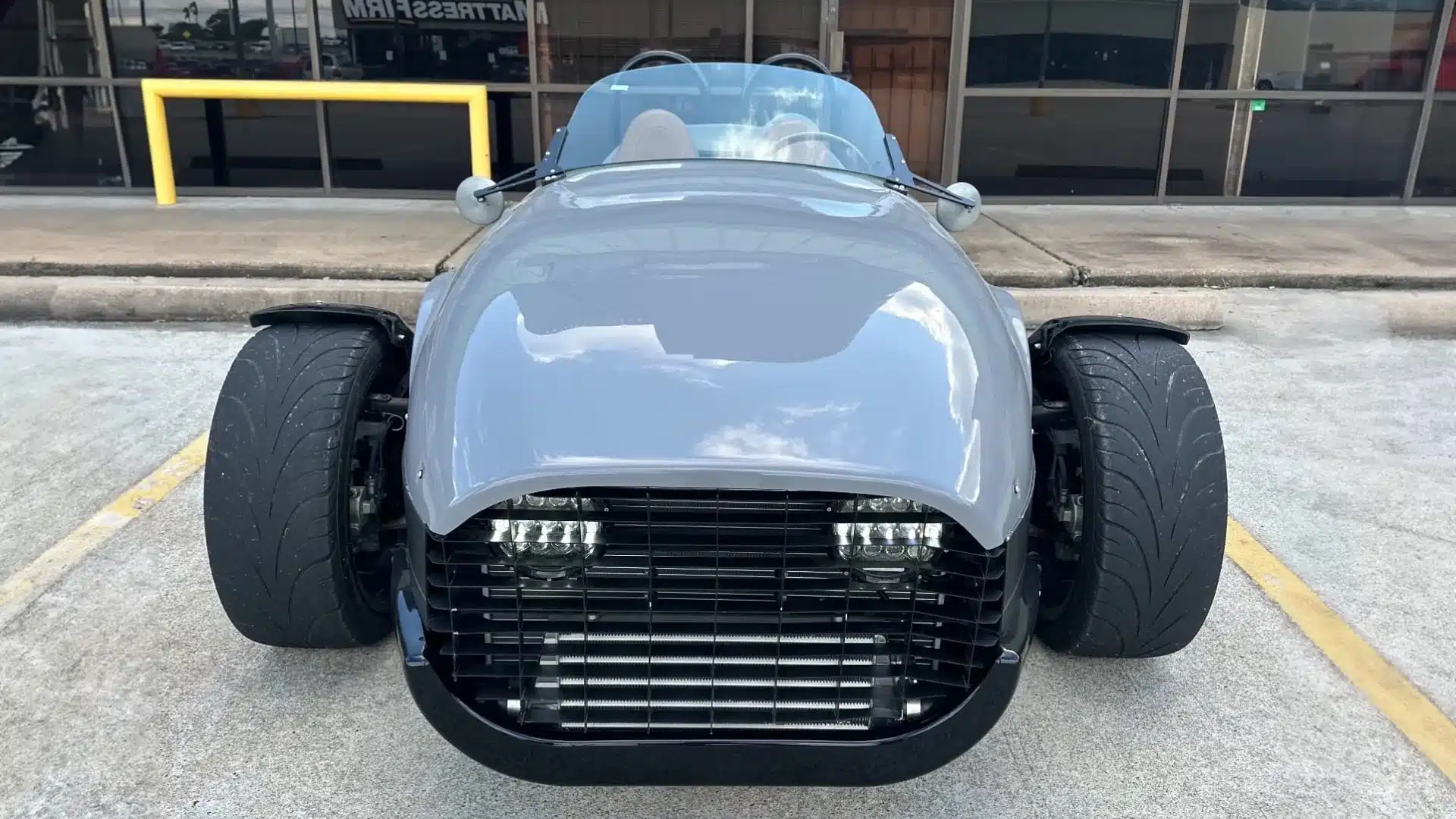 Vorderansicht einer grauen 2022 Vanderhall Venice mit zwei Vorderrädern auf einem Parkplatz.