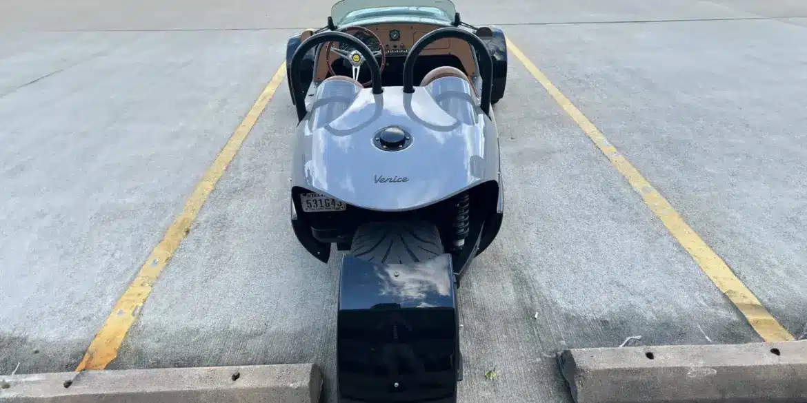 Heckansicht einer 2022 Vanderhall Venice in einer Parklücke, das einzelne Hinterrad und die Roadster-Karosserie sind gut sichtbar.