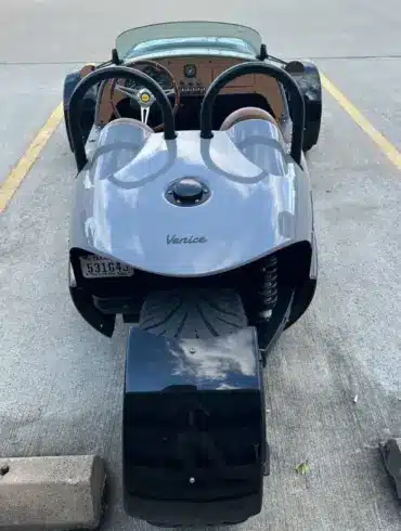 Heckansicht einer 2022 Vanderhall Venice in einer Parklücke, das einzelne Hinterrad und die Roadster-Karosserie sind gut sichtbar.