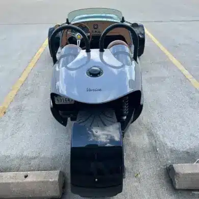 Heckansicht einer 2022 Vanderhall Venice in einer Parklücke, das einzelne Hinterrad und die Roadster-Karosserie sind gut sichtbar.