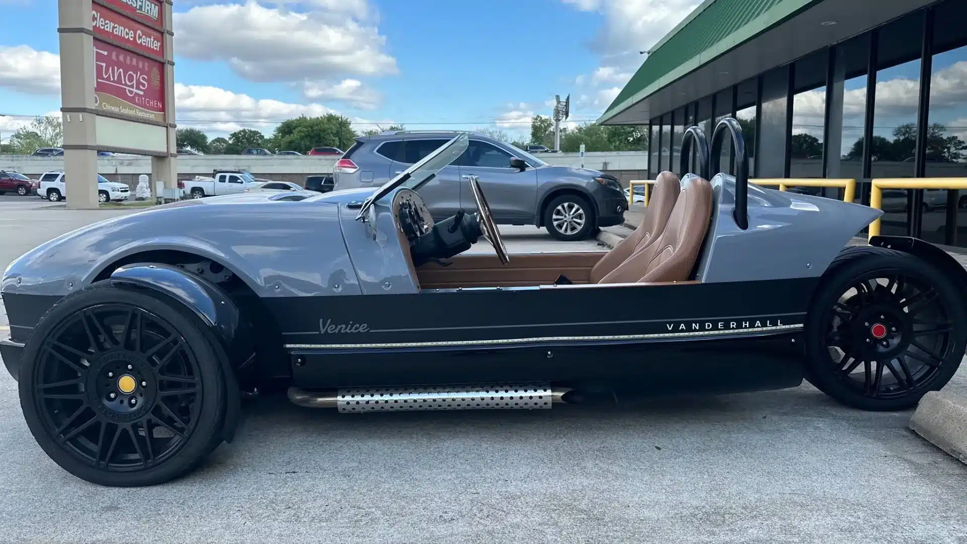 Vanderhall Venice 2022 als dreirädriger Roadster in Grau und Schwarz, Seitenansicht vor Geschäften geparkt.