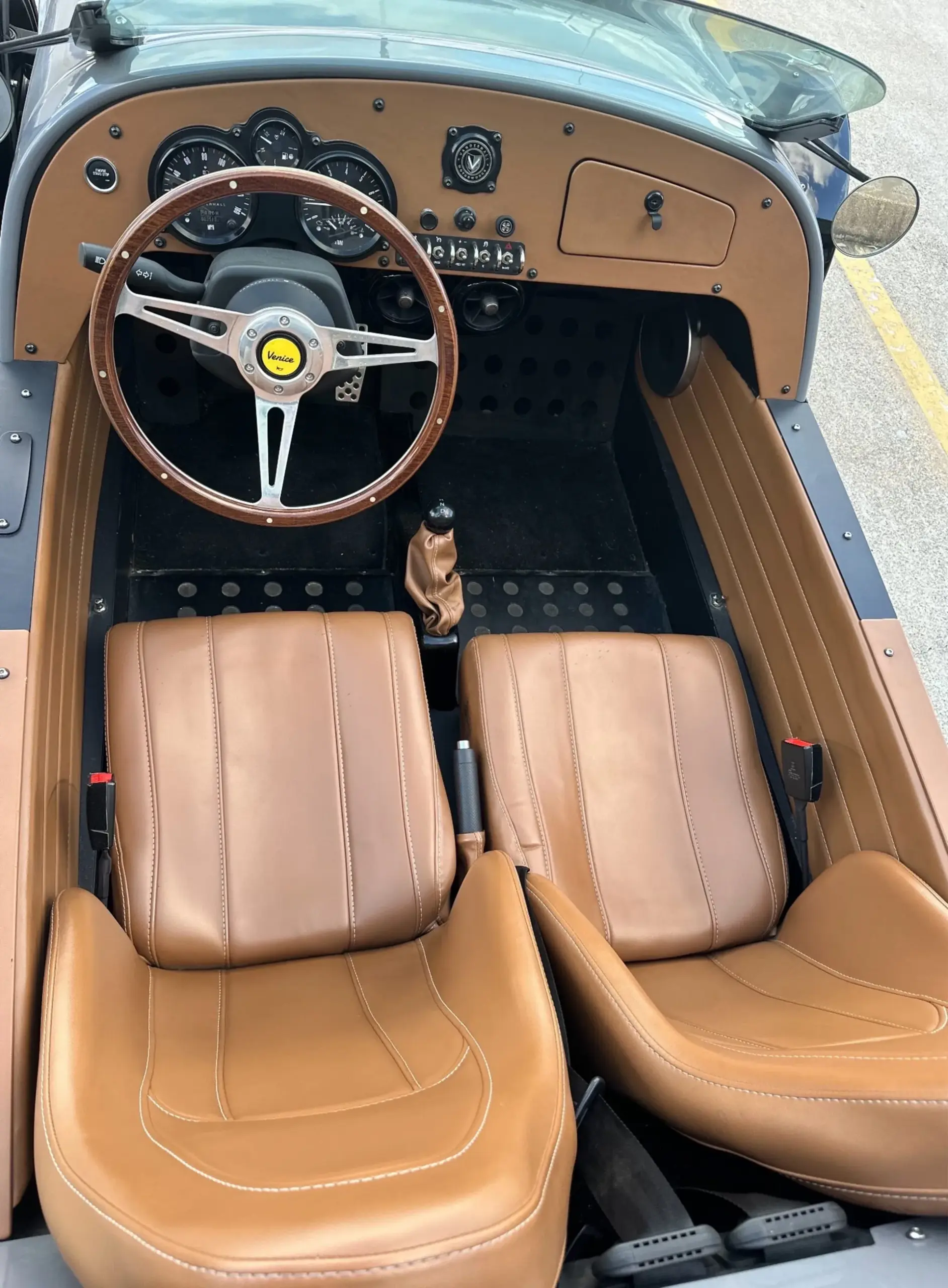 Interieur einer 2022 Vanderhall Venice, Blick auf Lenkrad, Armaturenbrett und zwei braune Ledersitze.