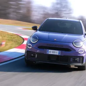 Frontansicht eines violetten Abarth 600e Scorpionissima auf einer Rennstrecke in Kurvenfahrt.