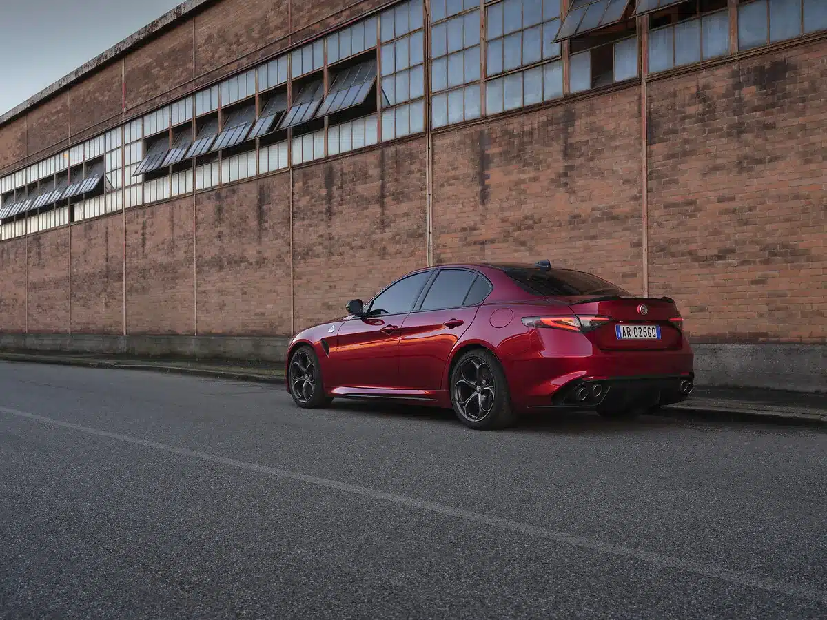 Alfa Romeo Giulia Quadrifoglio Collezione in dunklem Rot von hinten, geparkt vor einer Backsteinwand