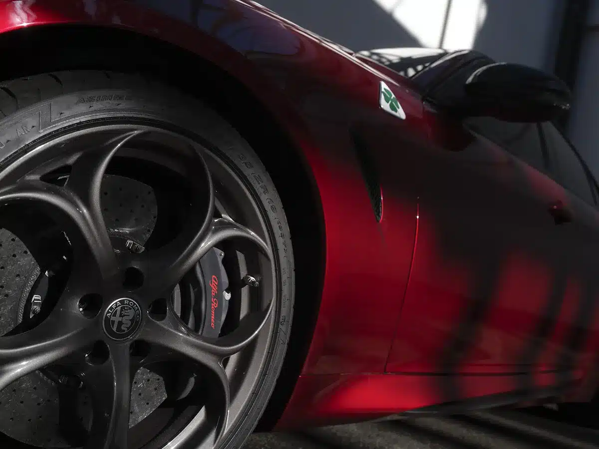 Nahaufnahme des Vorderrads einer Alfa Romeo Giulia Quadrifoglio Collezione mit Carbon-Keramik-Bremse und burnished eloxiertem Bremssattel mit rotem Alfa-Romeo-Schriftzug, erkennbar im speziellen Rotton der Sonderserie.