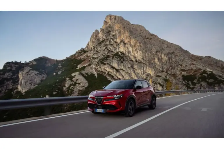 Alfa Romeo Junior MY26 Sport Speciale in Rot fährt auf einer Bergstraße, im Hintergrund hohe Felswände.
