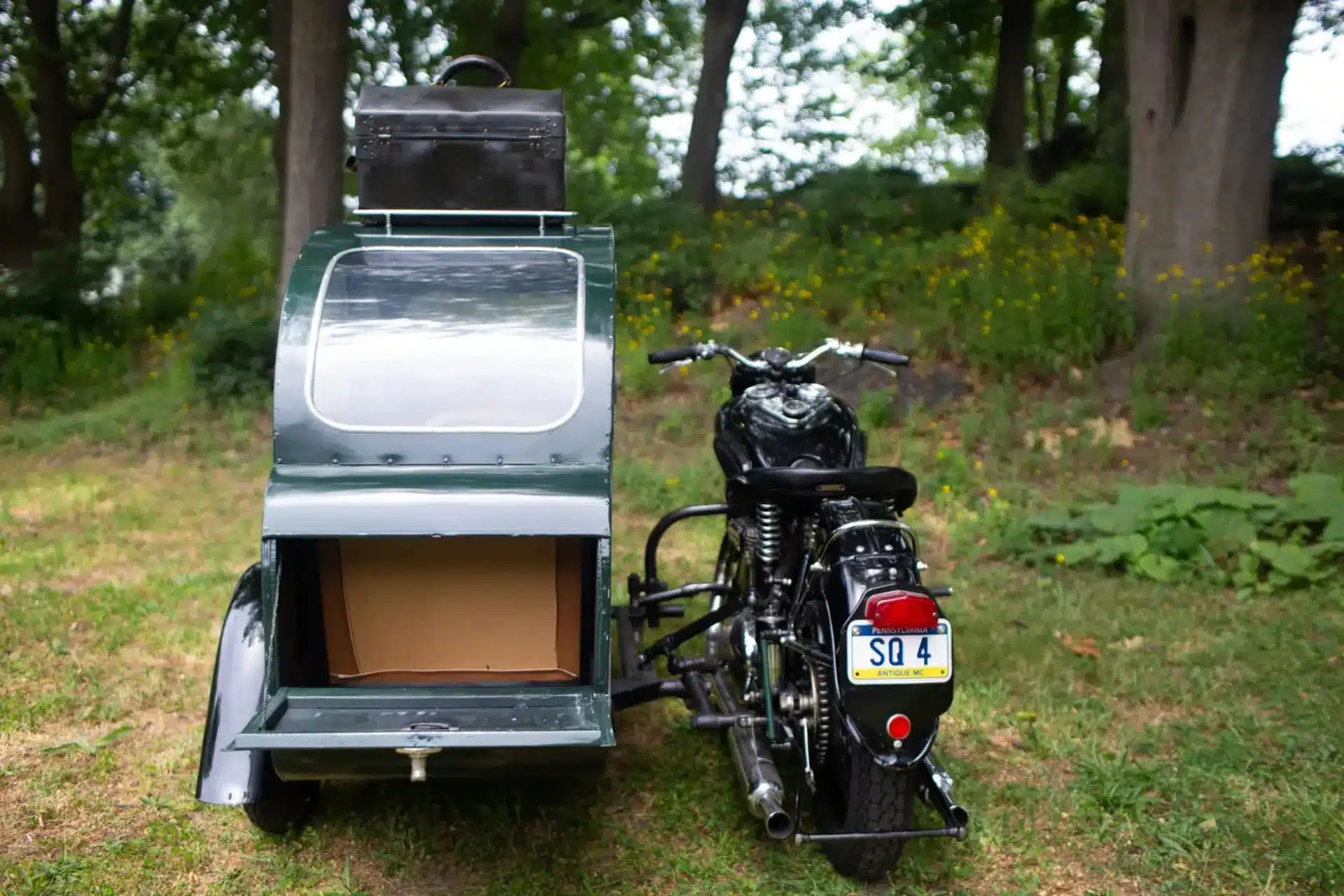 Ariel Square Four Motorrad mit Watsonian-Seitenwagen, von hinten gesehen, auf einer Wiese mit Bäumen im Hintergrund.