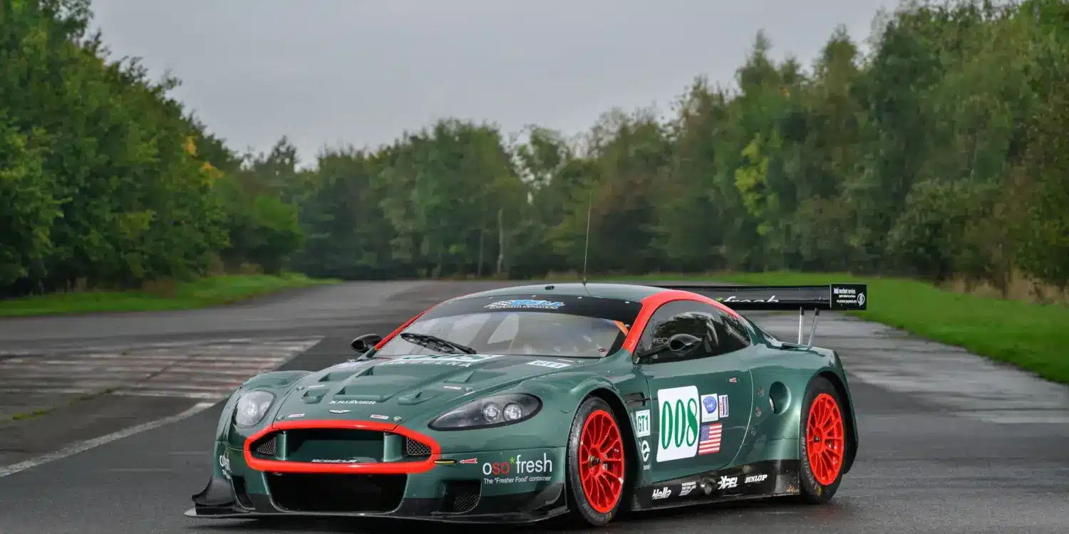 Aston Martin DBR9/5 Rennwagen von 2006 in Grün mit roten Akzenten und Startnummer 008, fotografiert auf einer asphaltierten Strecke.