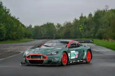 Aston Martin DBR9/5 Rennwagen von 2006 in Grün mit roten Akzenten und Startnummer 008, fotografiert auf einer asphaltierten Strecke.