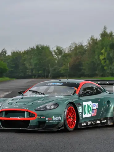 Aston Martin DBR9/5 Rennwagen von 2006 in Grün mit roten Akzenten und Startnummer 008, fotografiert auf einer asphaltierten Strecke.