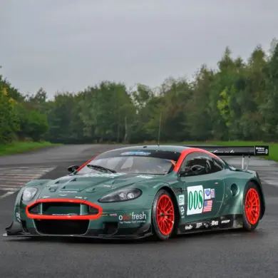Aston Martin DBR9/5 Rennwagen von 2006 in Grün mit roten Akzenten und Startnummer 008, fotografiert auf einer asphaltierten Strecke.